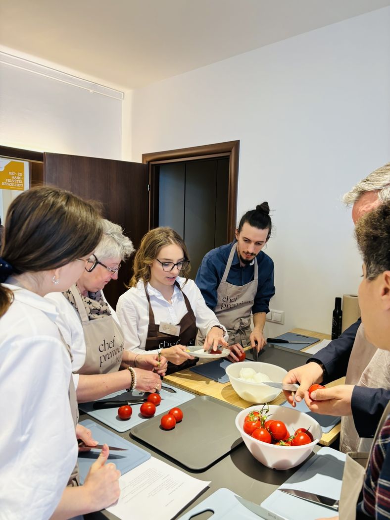 Résztvevők paradicsomot szeletelnek a séffel a közös főzésen
